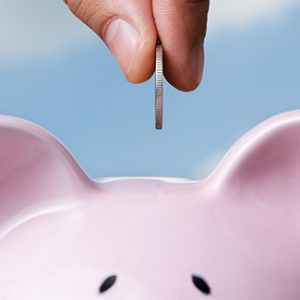 Employee dropping a coin in a pink piggy bank