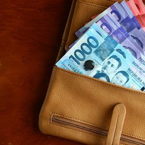 Brown wallet spread open with 1,000, 100, and 50 Philippine peso bills
