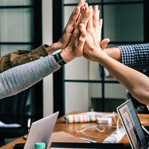 Team doing a celebratory high five as they achieve their team goal while having a harmonious work-life balance